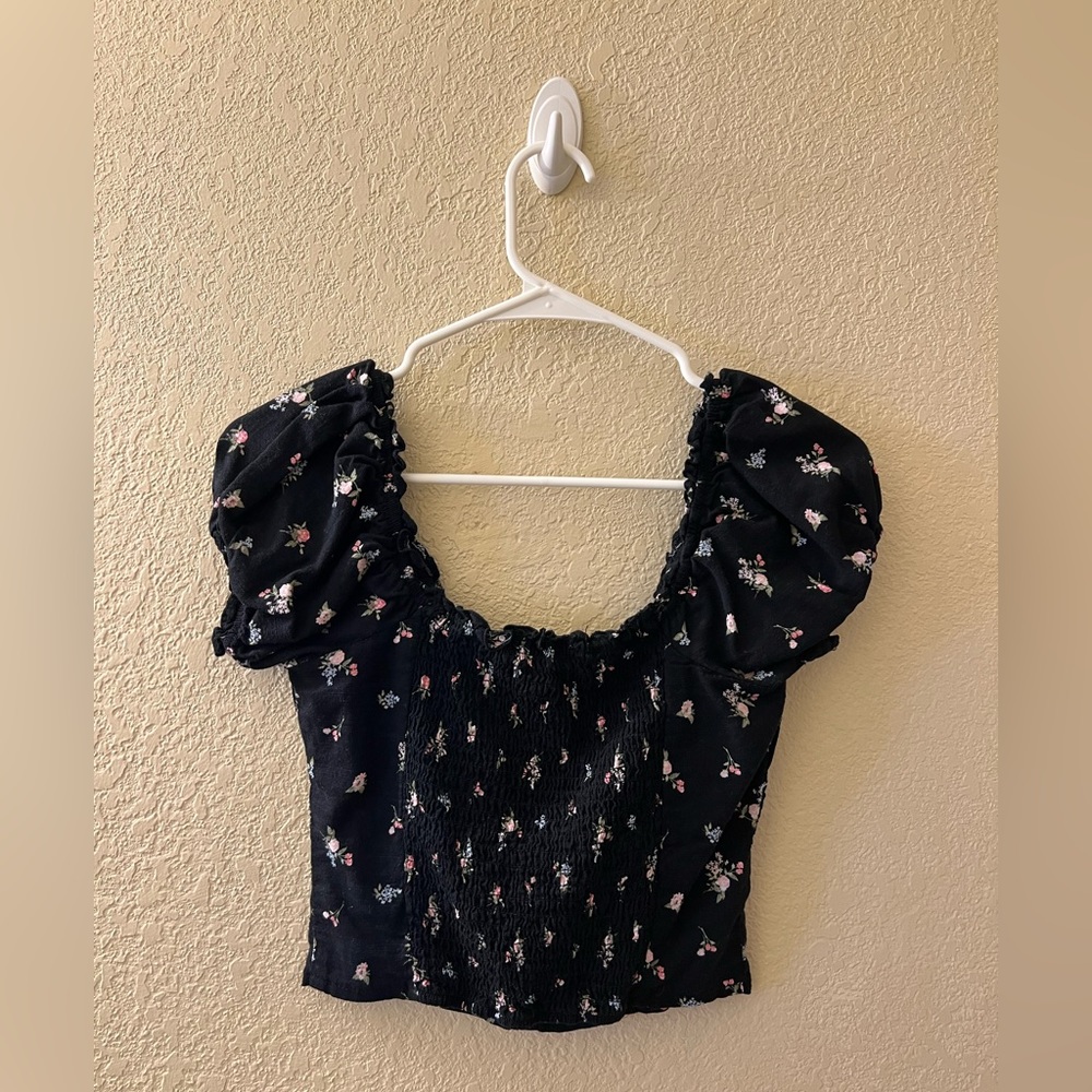 Black shirt with pink and blue flower detailing. Black buttons down the center.